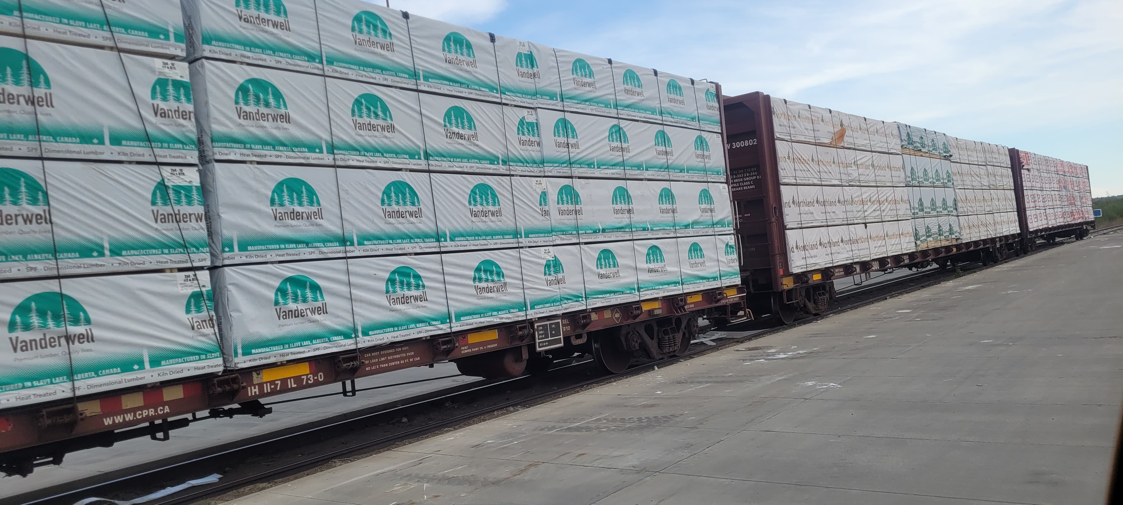 Wide shot of a long freight train carrying lumber